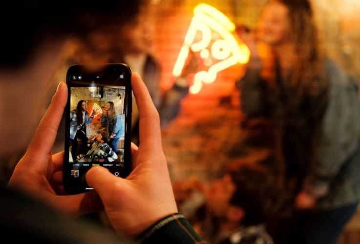 A group of friends pose for a picture (taken with a mobile phone) at Pizza Boutique, Belfast