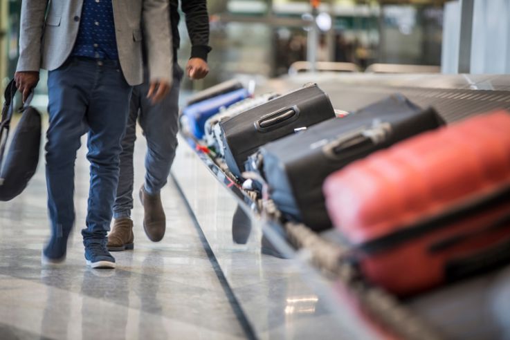 Wheeled suitcase on a luggage belt at the airport terminal.